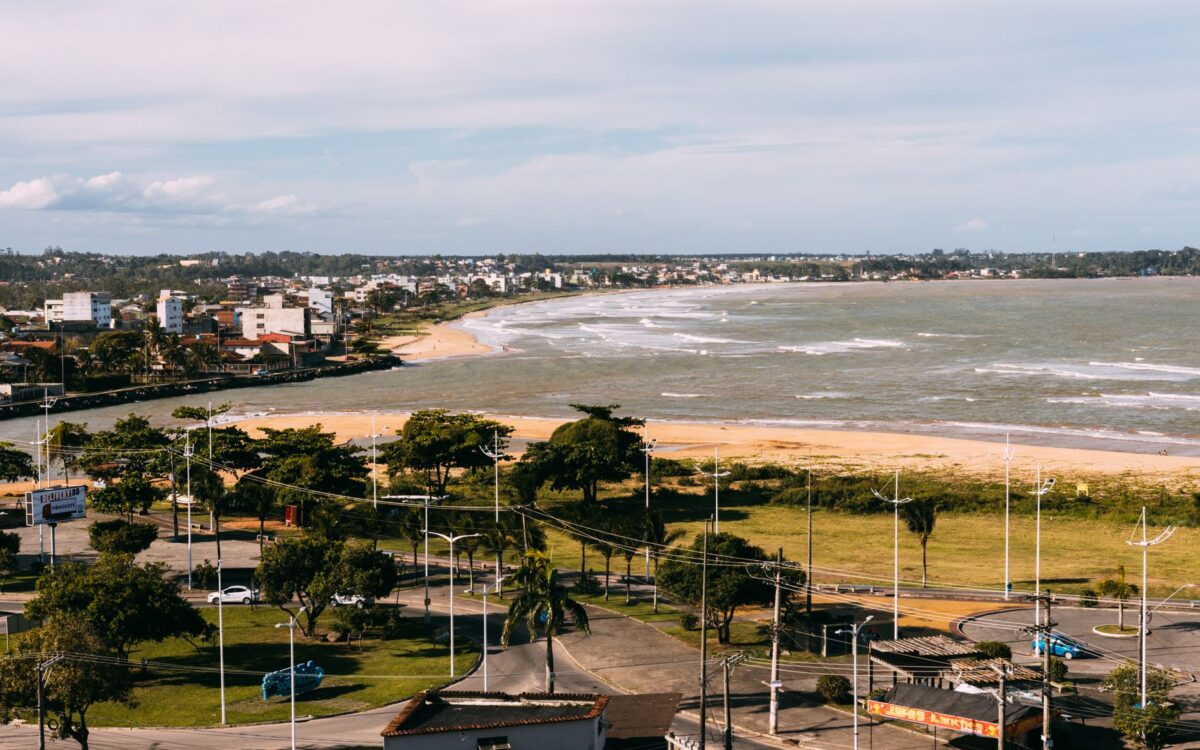 Vista aérea de uma cidade costeira com praia, oceano e edifícios modernos em um dia ensolarado